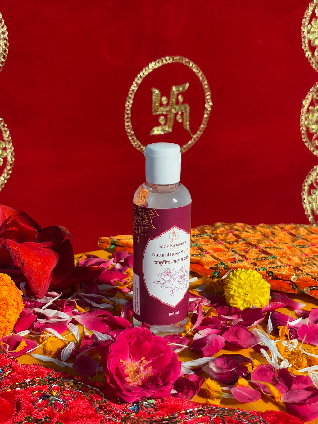 Bottle of Satya Sanatani Natural Rose Water with puja flowers and Swastik backdrop
