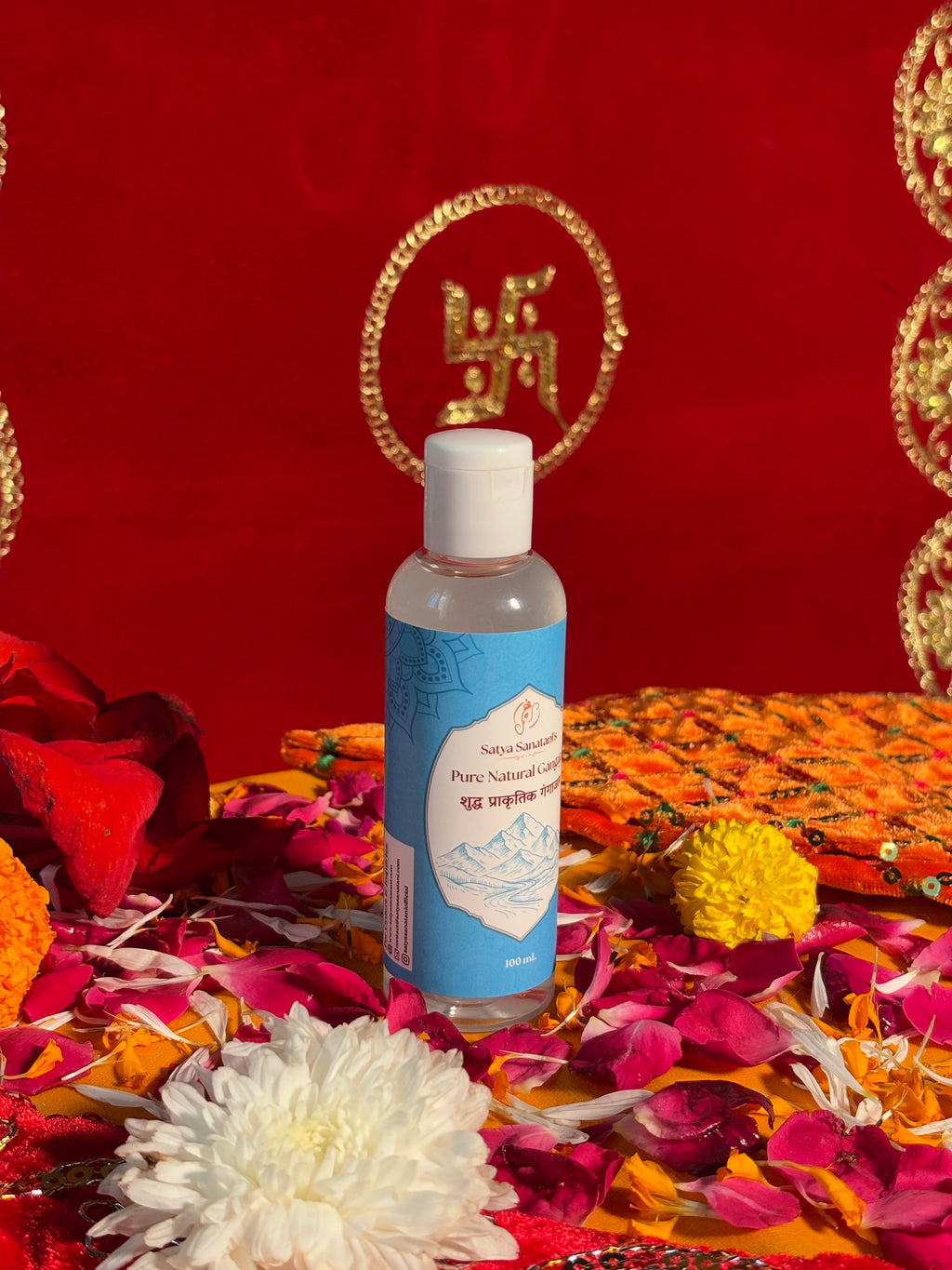 Bottle of Satya Sanatani Pure Gangajal with puja flowers and Swastik backdrop
