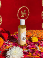 Bottle of Satya Sanatani Chameli Oil with puja flowers and Swastik backdrop