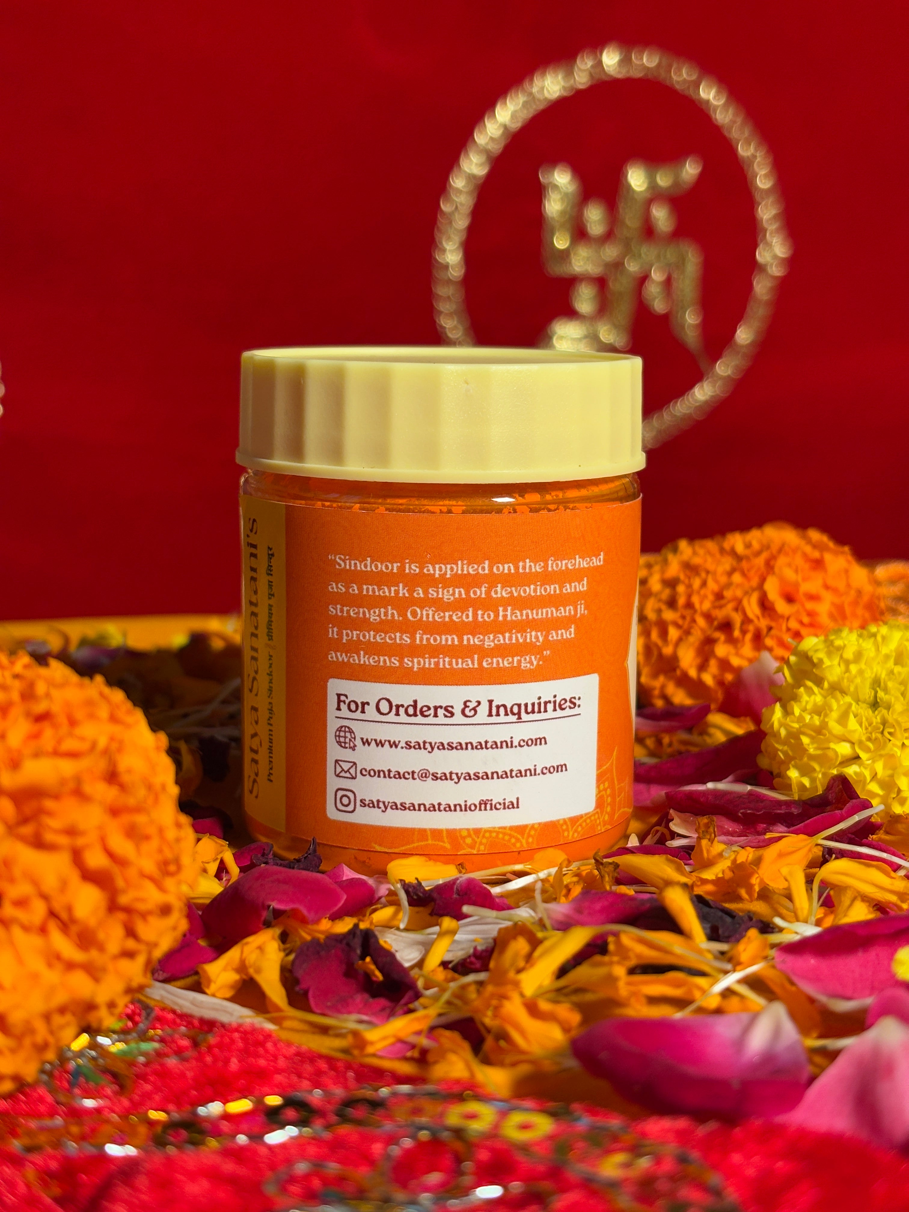 Open jar of bright orange Sindoor displayed with marigold petals