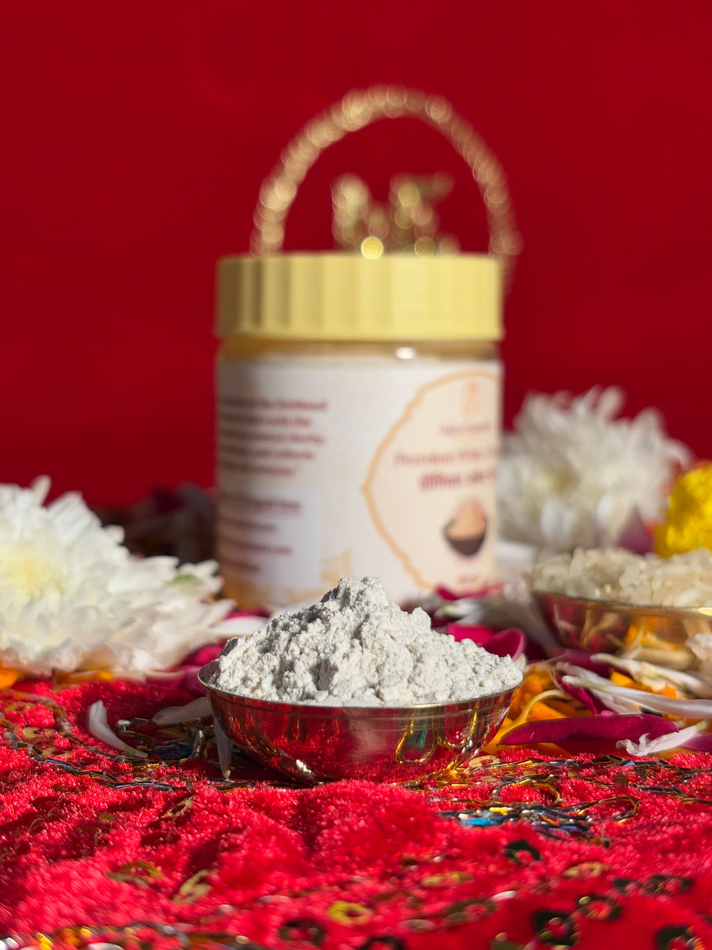 White Chandan powder jar surrounded by rose and marigold flowers for rituals
