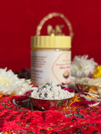 White Chandan powder jar surrounded by rose and marigold flowers for rituals