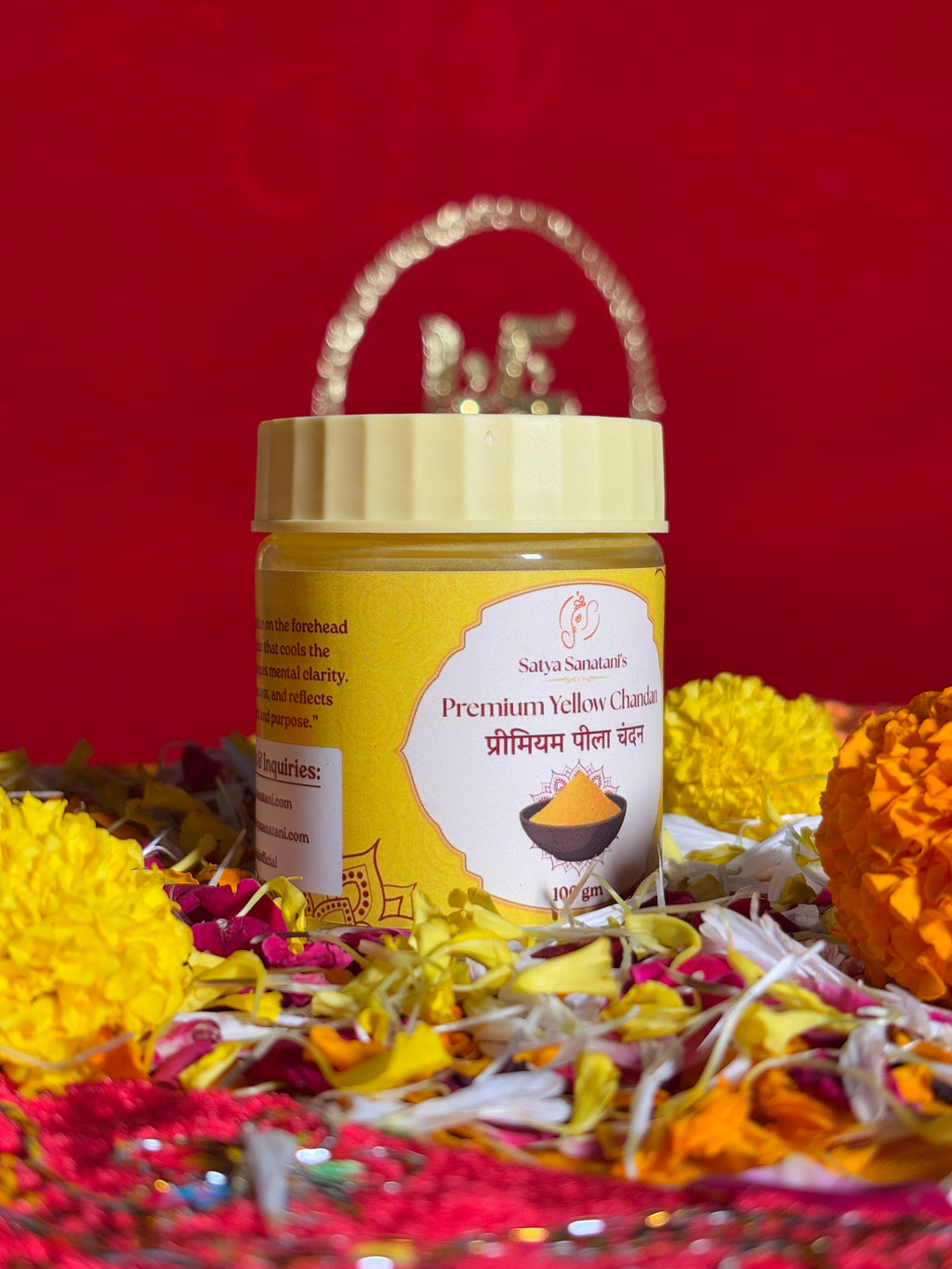 Satya Sanatani Yellow Chandan 100gm jar with puja flowers and Swastik backdrop