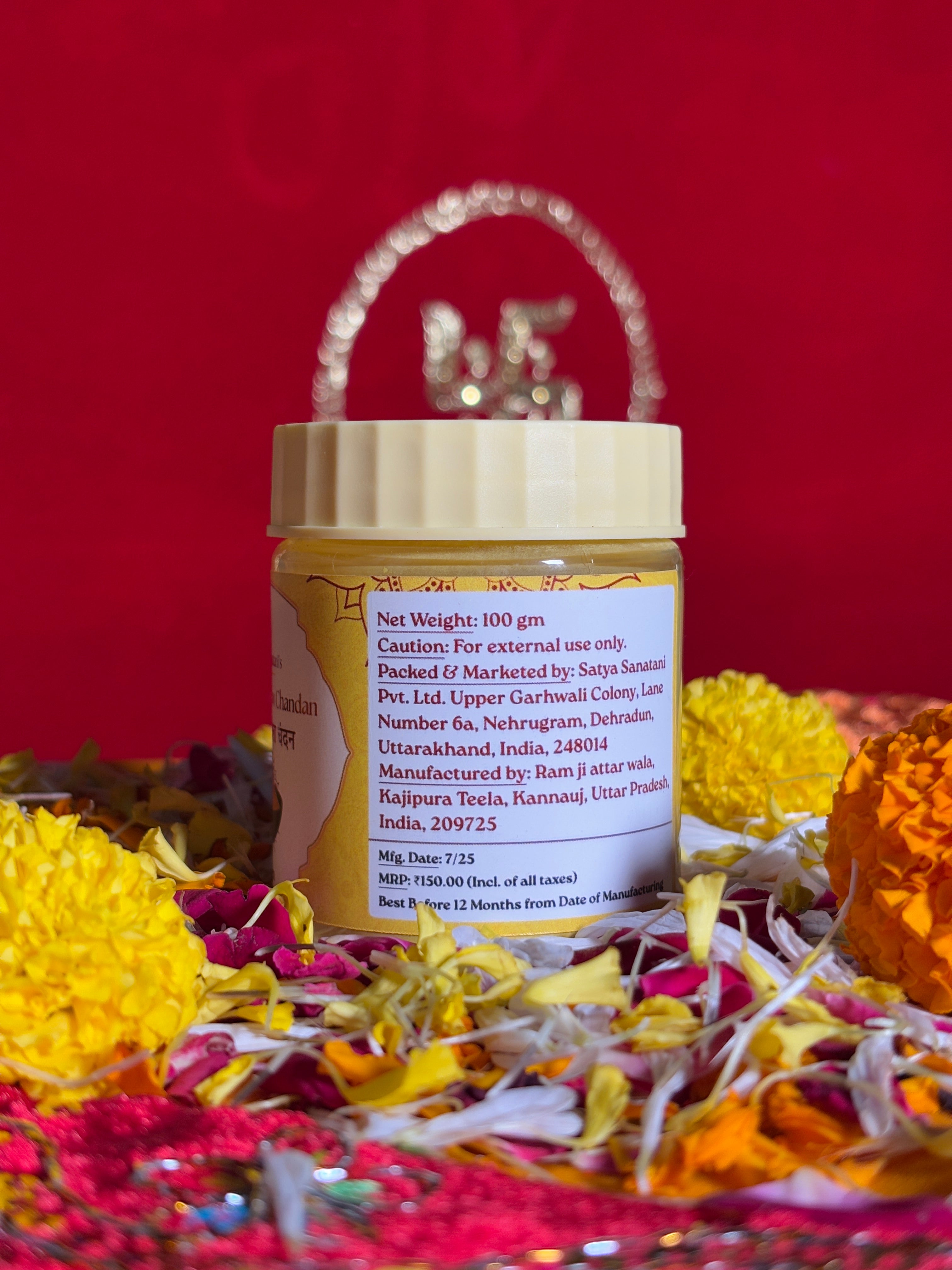 Open jar of yellow sandalwood powder displayed with marigold petals