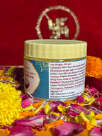 Open jar of Bhimseni camphor crystals placed with marigold and rose petals