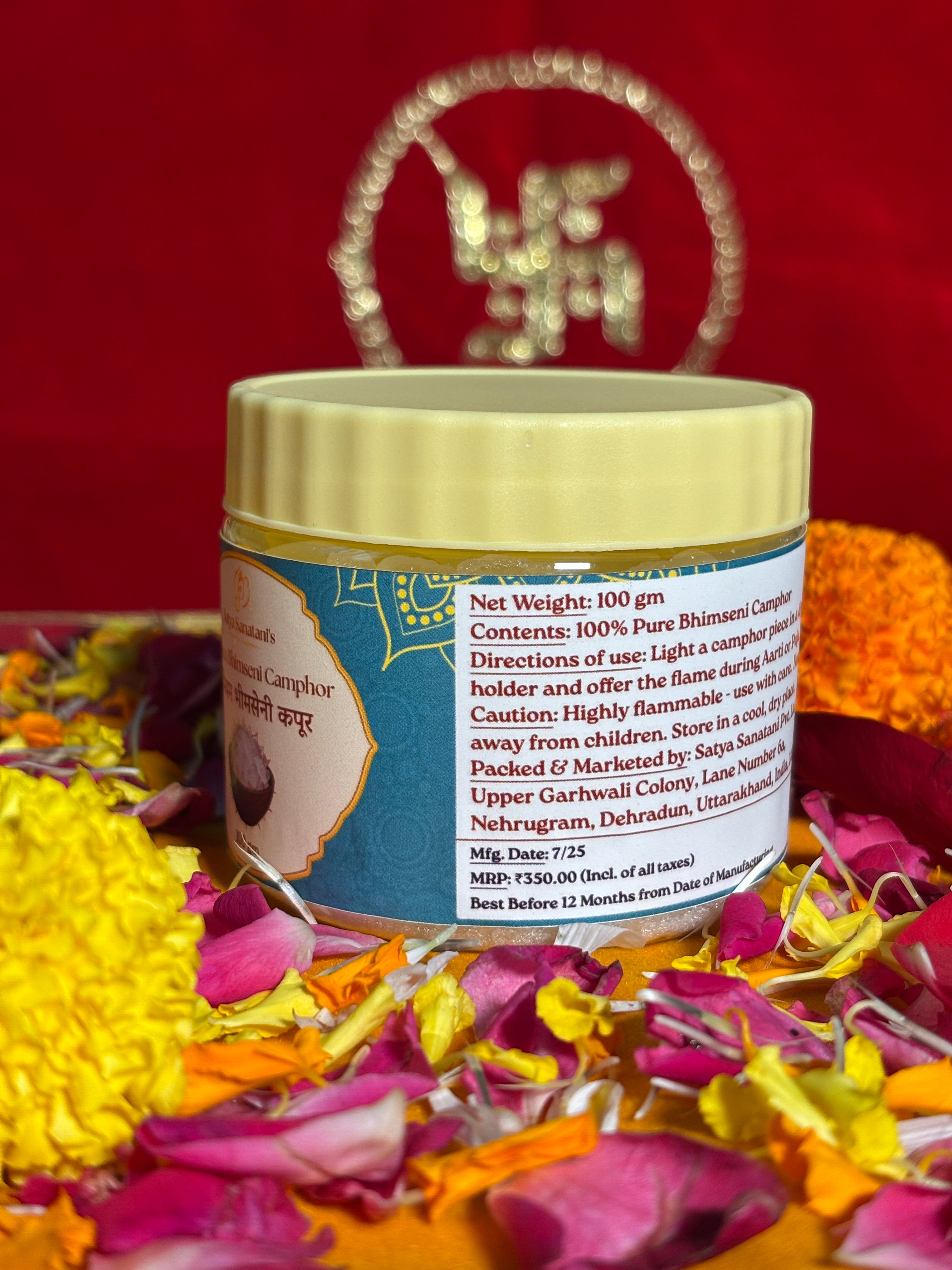 Open jar of Bhimseni camphor crystals placed with marigold and rose petals