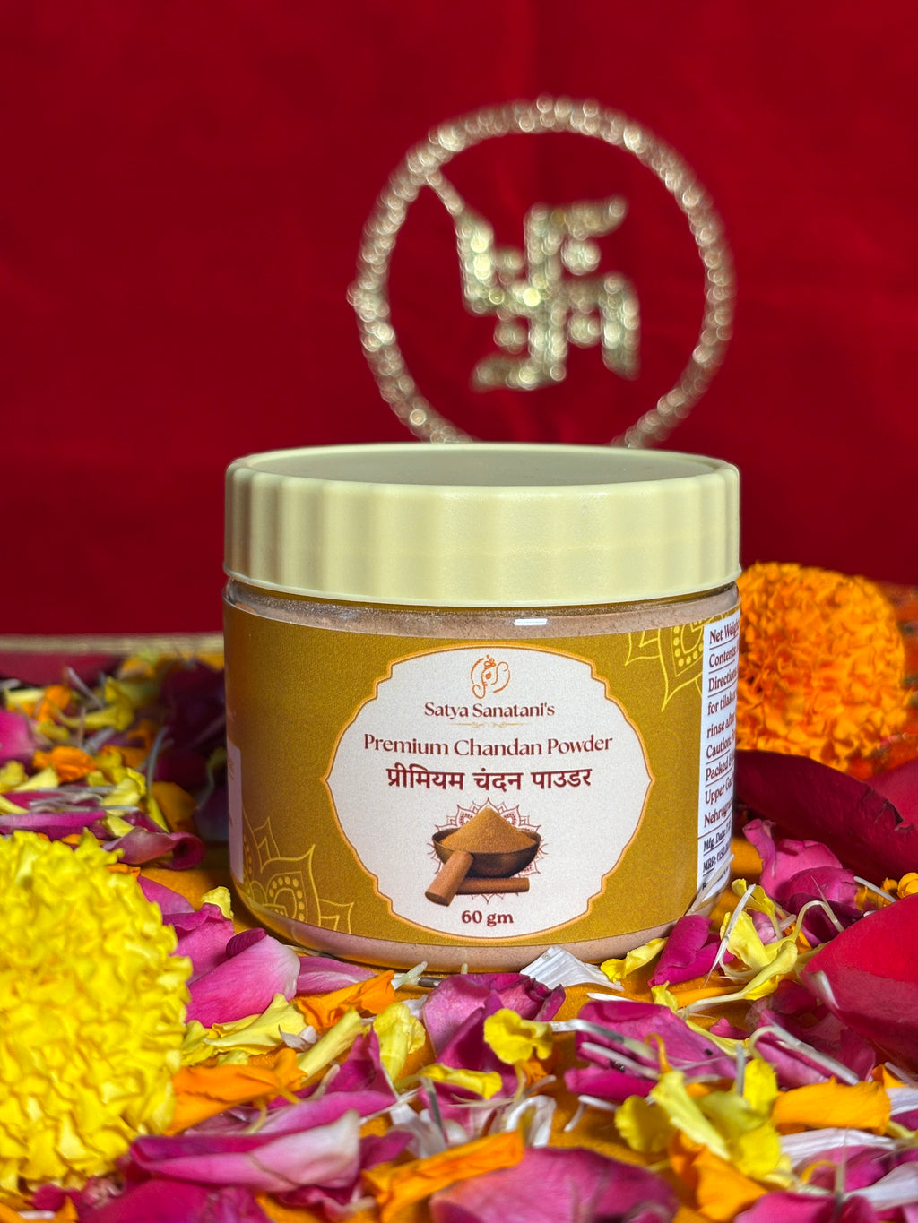 Open jar of sandalwood powder surrounded by marigold and rose petals