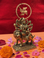 Brass idol of Maa Durga as Mahishasura Mardini riding a lion with weapons, decorated with flowers