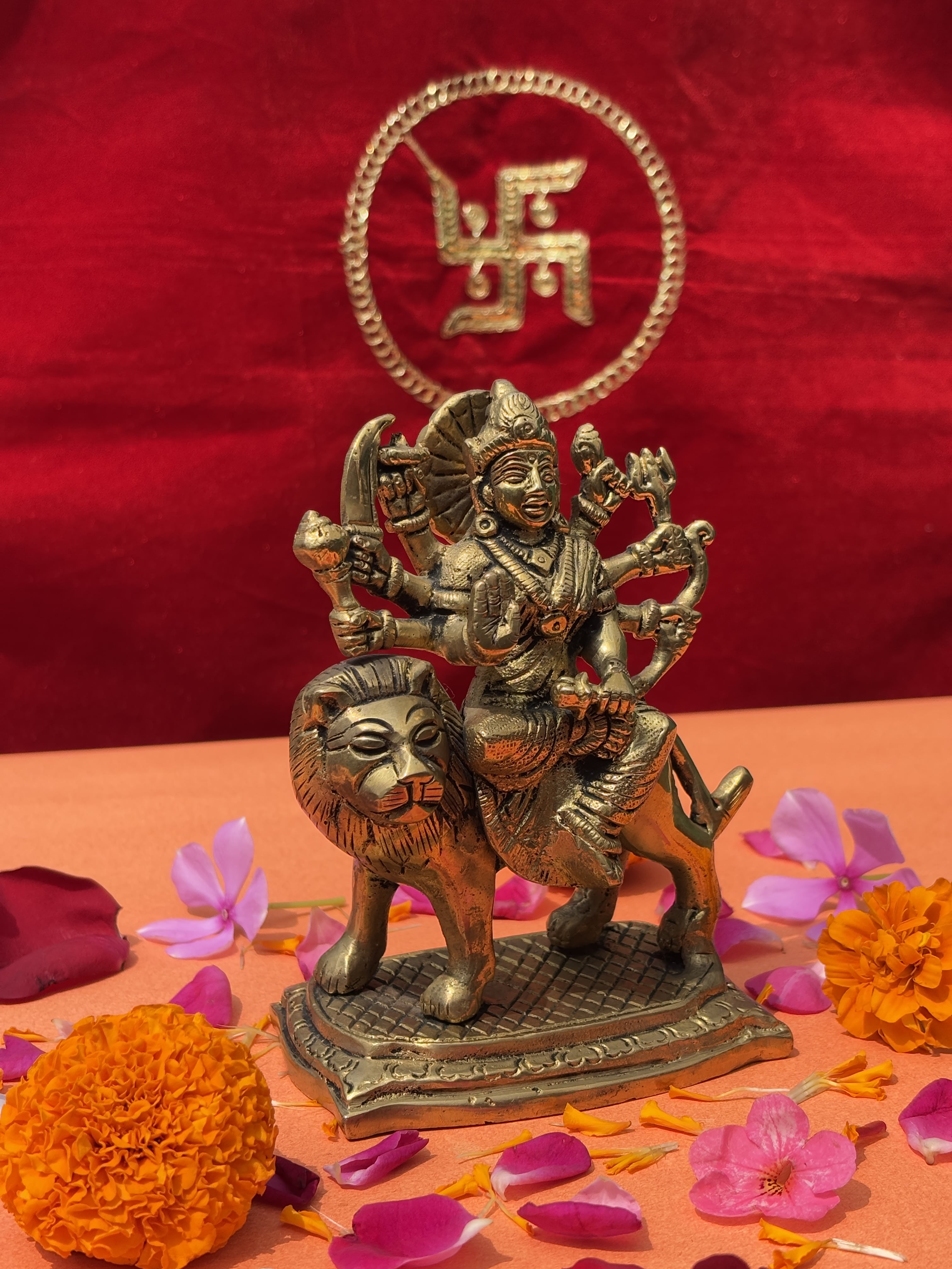 Brass idol of Maa Durga as Mahishasura Mardini riding a lion with weapons, decorated with flowers